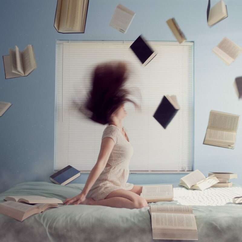 woman on her bed stressed out throwing books