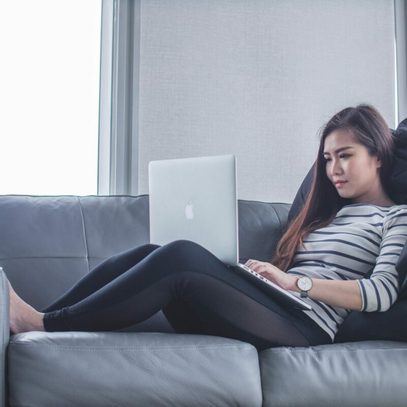 woman laying on couch with laptop on her lap