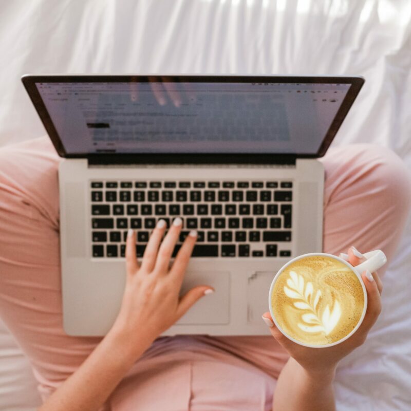 Woman with coffee and laptop searching for online cognitive coaching