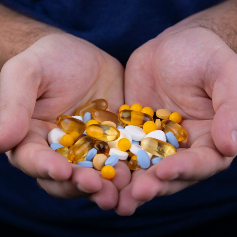 man holding a variety of pills in his hand